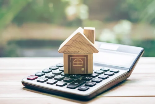 calculator with a miniature house sitting on top of it