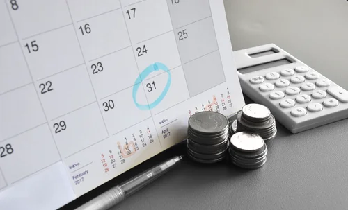 calendar and calculator next to a stack of money